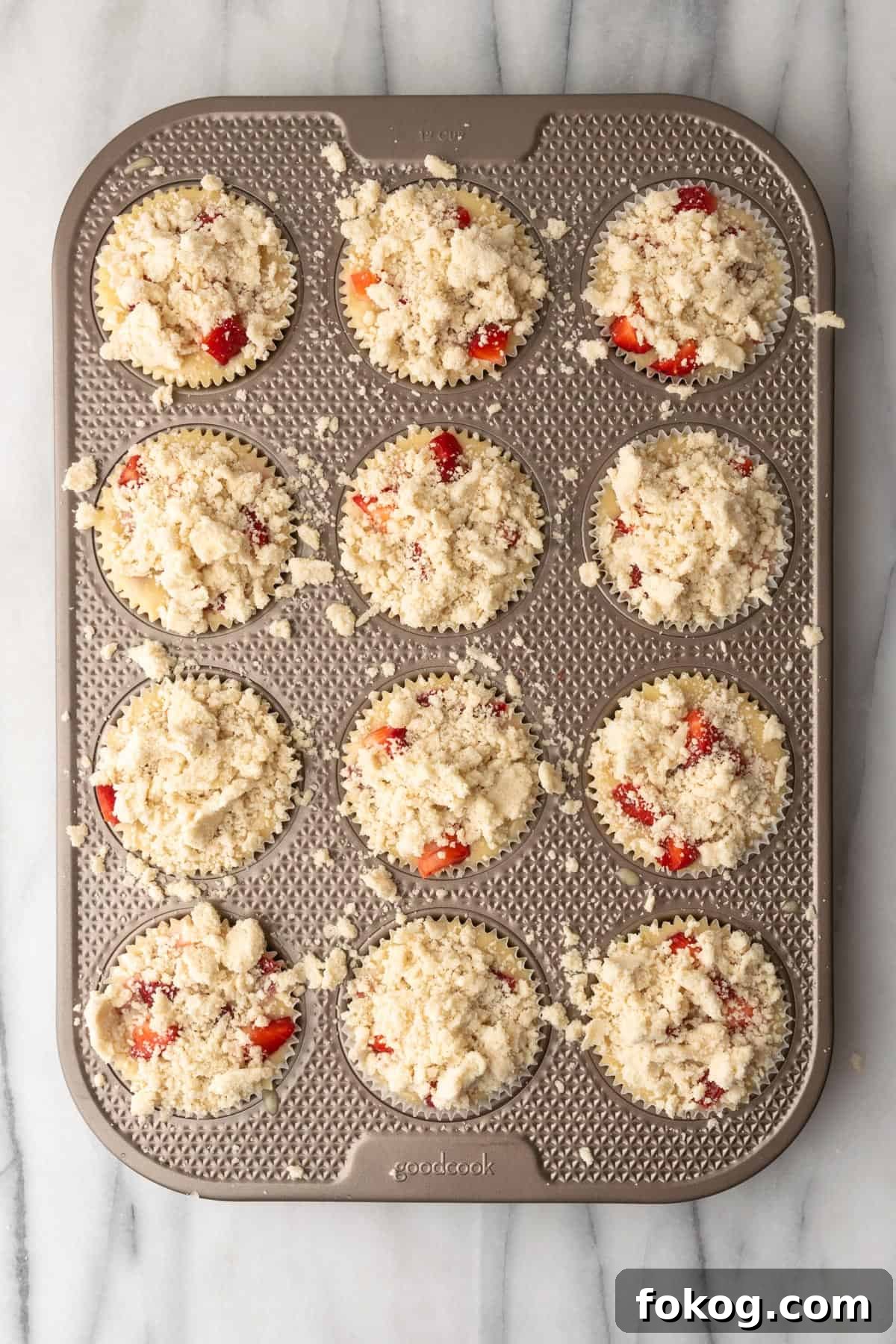Gluten-Free Strawberry Muffins Recipe with Moist, Tender Crumbs 11 A muffin tin filled with unbaked strawberry muffin batter topped with crumble topping.