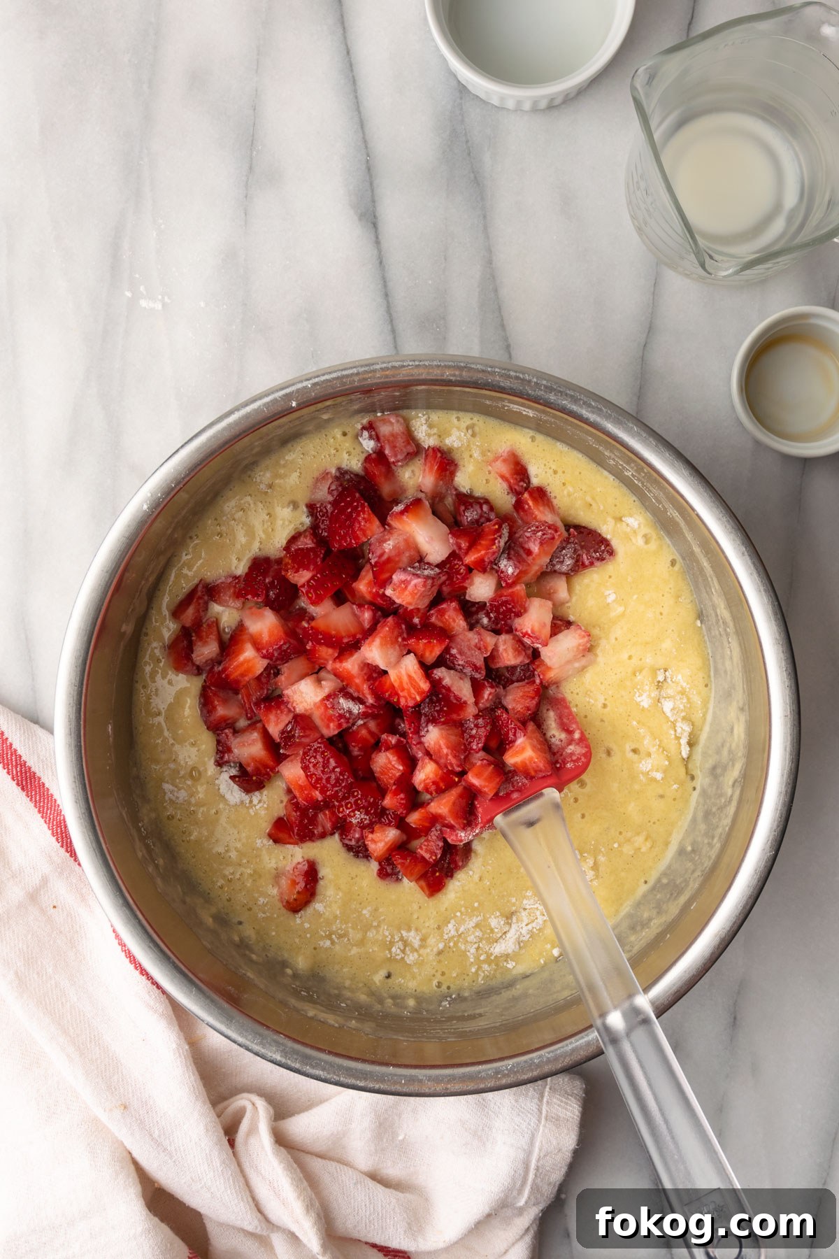 Gluten-Free Strawberry Muffins Recipe with Moist, Tender Crumbs 9 Fresh strawberries added to a bowl of muffin batter.