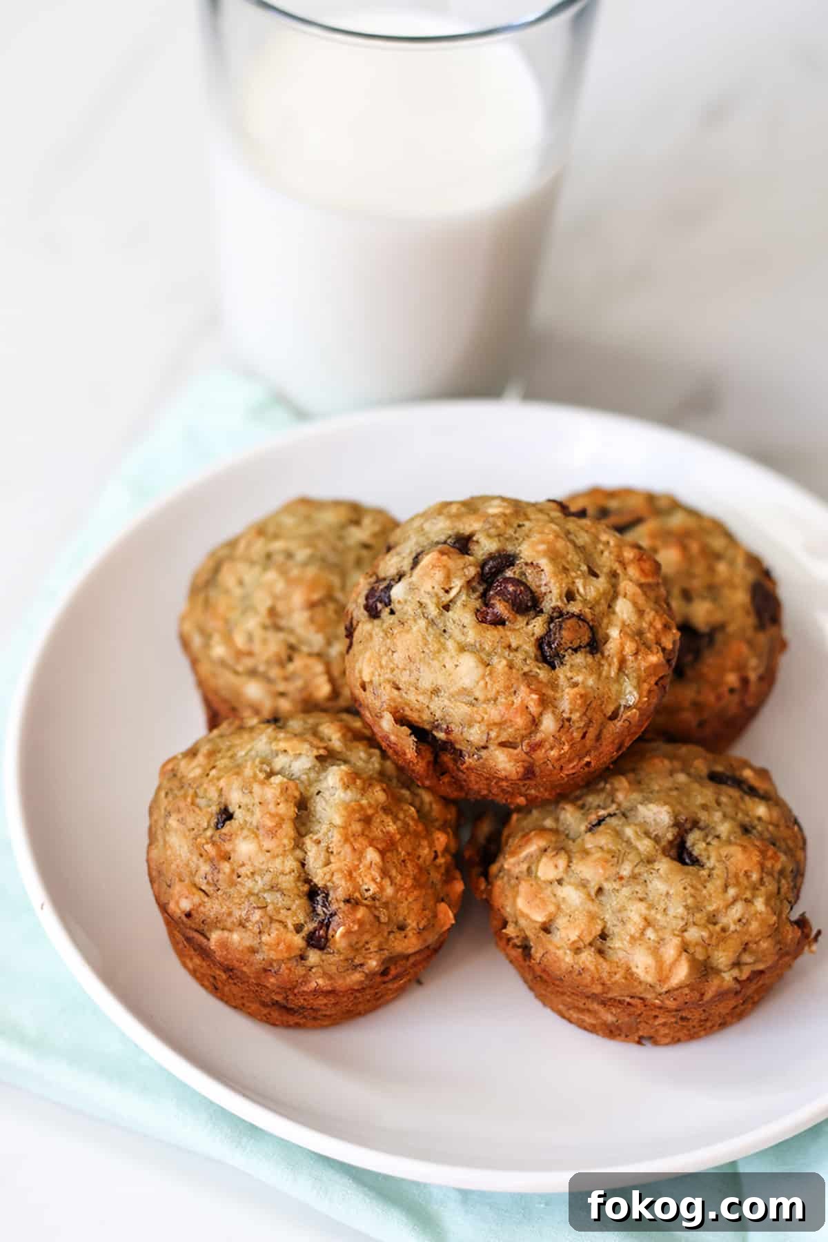 A plate with banana oat muffins and a glass of milk. 