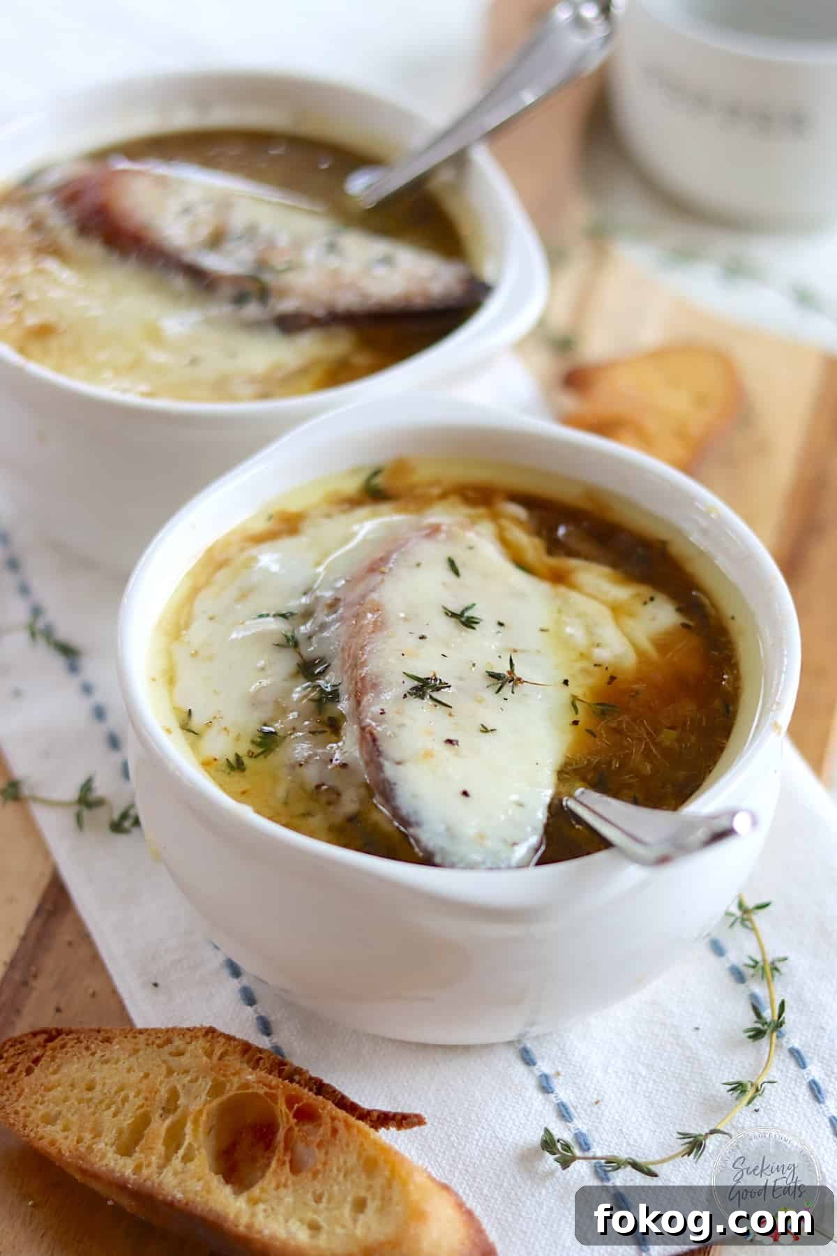 French onion soup in a white bowl with a crouton and melted gruyere cheese.