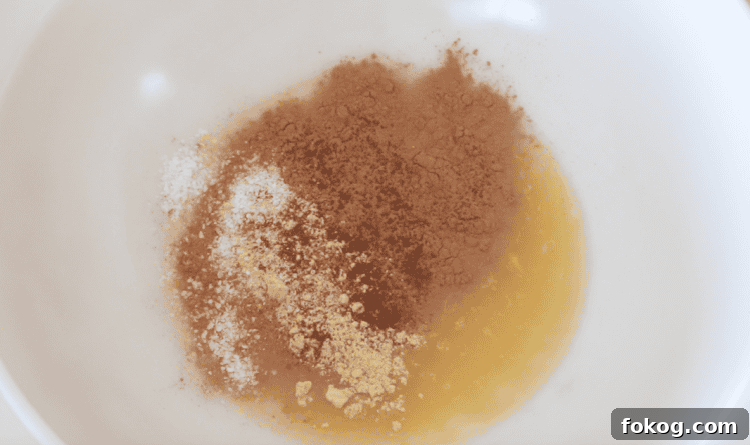 Egg and sugar mixed with gingerbread spices in mixing bowl.