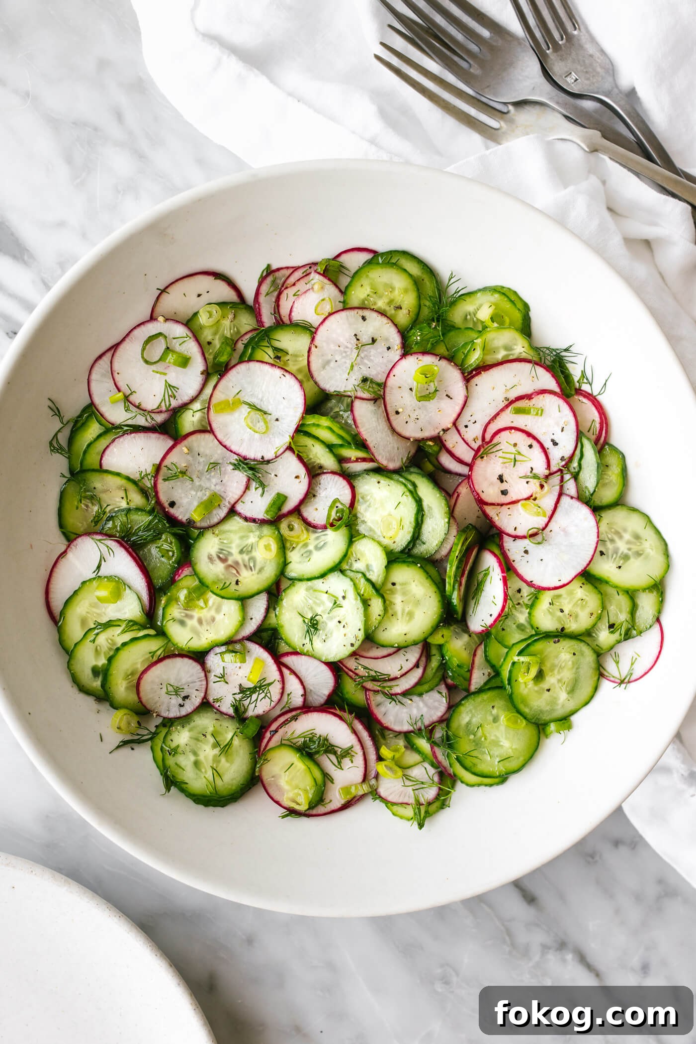 40+ Low-Carb Recipes for Weight Loss and Blood Sugar Control 10 A white bowl of cucumber radish salad next to forks.