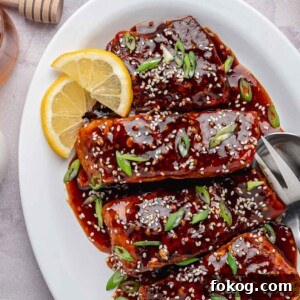 The final, finished Spicy Honey Garlic Salmon in a white serving dish with a thick, caramelized glaze.