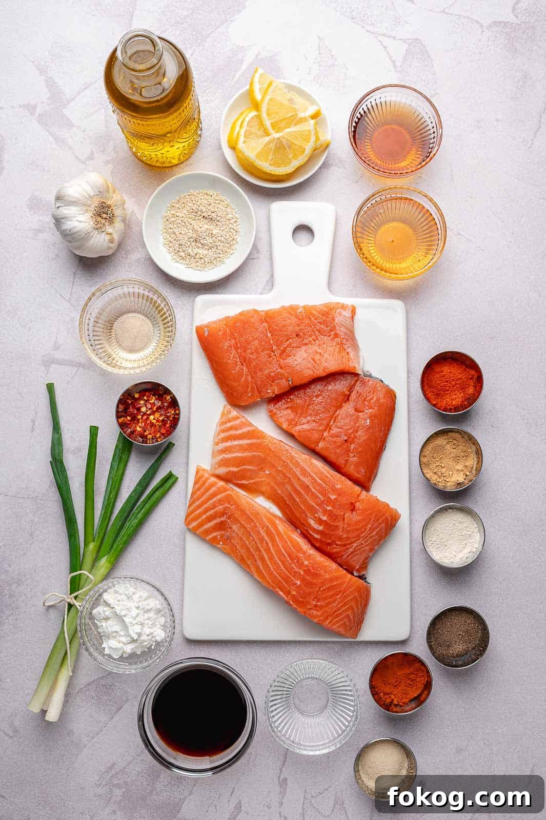 Ingredients for Spicy Honey Garlic Salmon arranged on a counter: salmon fillets, honey, soy sauce, spices, garlic, sesame oil, and green onions.