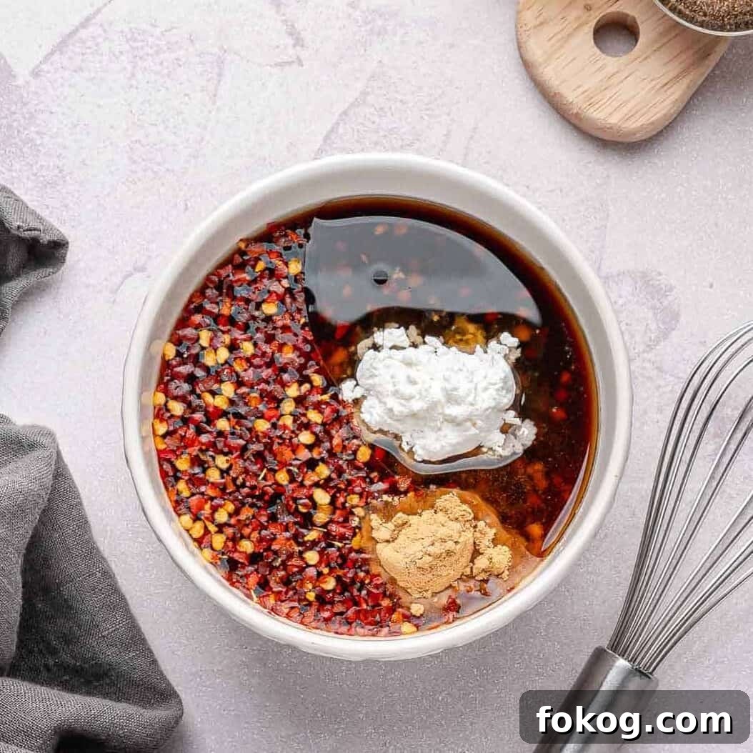 Sauce ingredients being whisked together: honey, soy sauce, rice vinegar, sesame oil, garlic, cornstarch, and chili flakes.