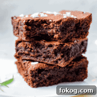A white plate with three cannabis brownies stacked on top, garnished with a cannabis leaf