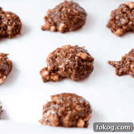 A white countertop with a cutting board topped with a white plate topped with three no-bake rocky road cannabis cookies