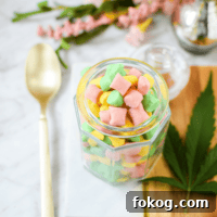 A white counter top with a gold spoon and a glass jar filled with cannabis butter mints.