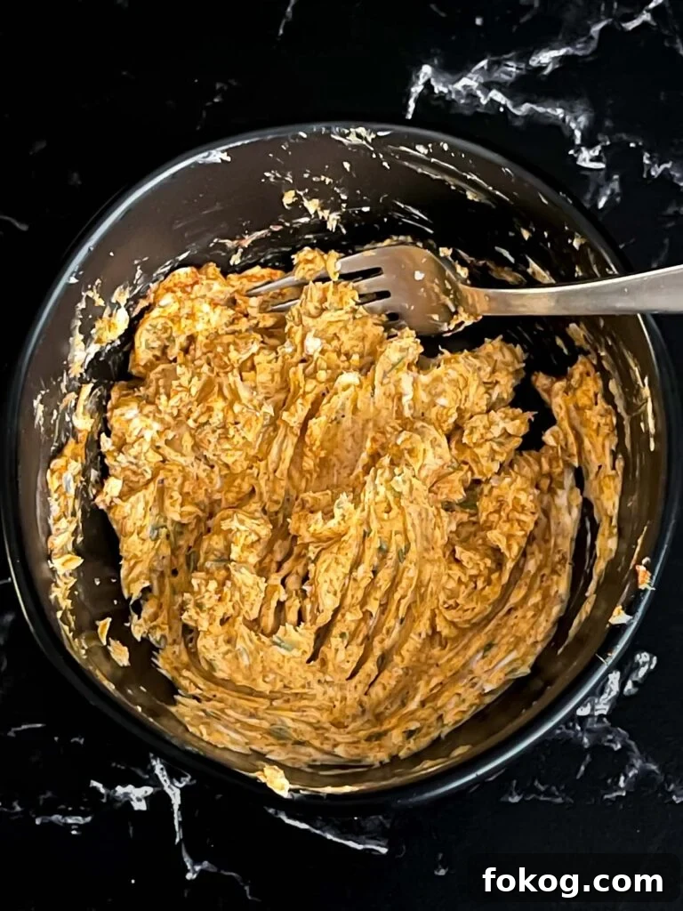 Lemon herb compound butter combined in a dark bowl on a dark surface.