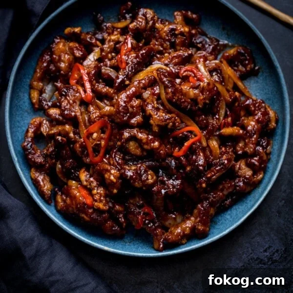 Square image of crispy chilli beef in a blue bowl