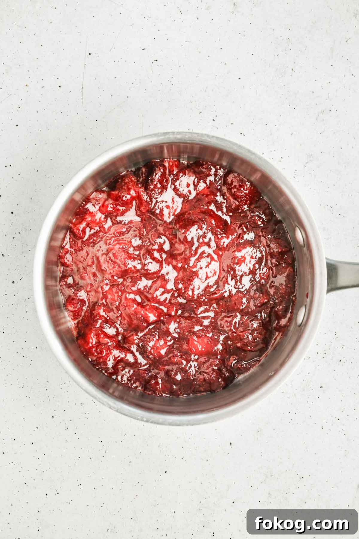 strawberries cooking down into a smooth strawberry puree in a small saucepan