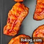 Smoked Thin-Cut Pork Chops on a Traeger Grill 12 Juicy, smoky Traeger smoked thin pork chops brushed with BBQ sauce, resting on a baking sheet.