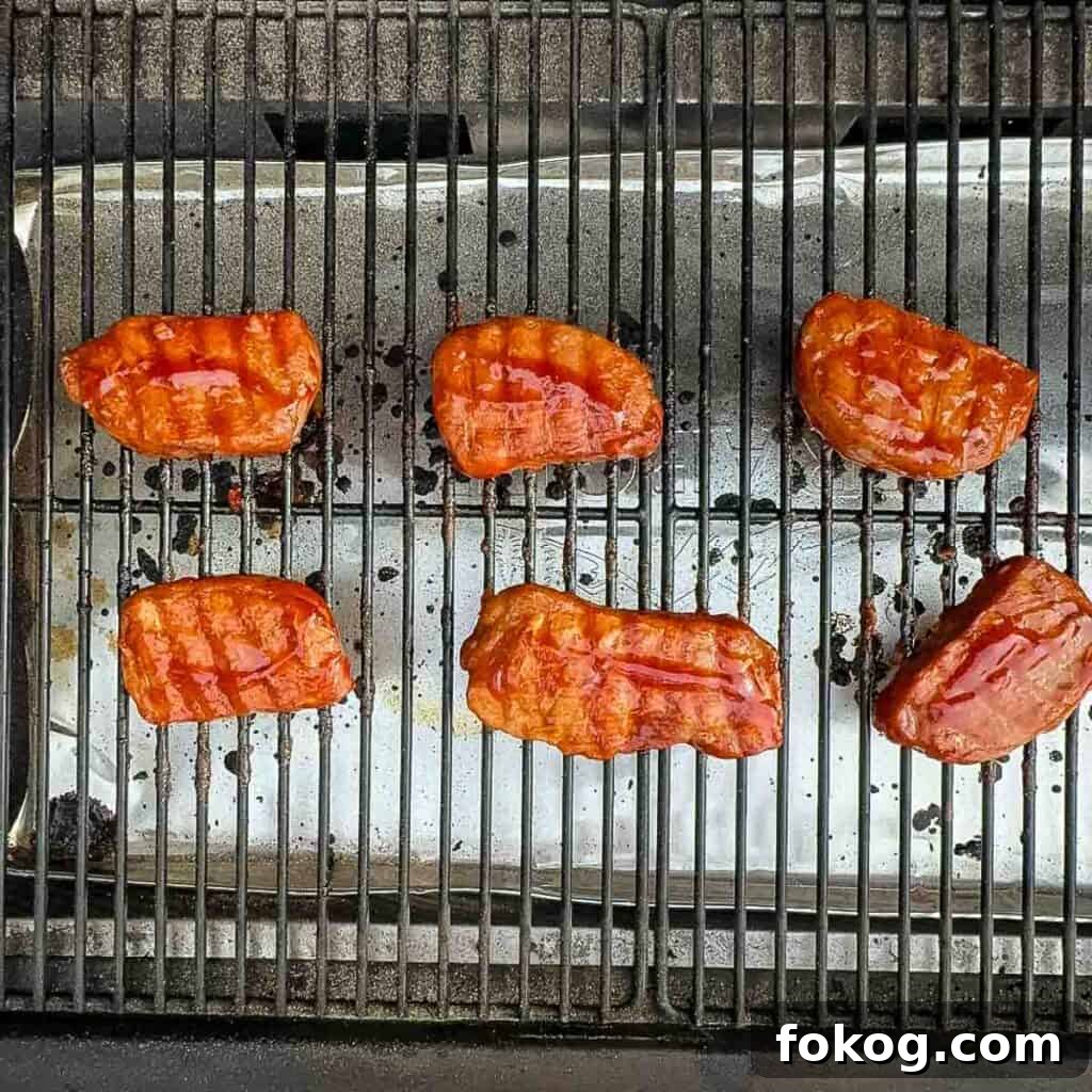 Smoked Thin-Cut Pork Chops on a Traeger Grill 7 Pork chops on the grill being brushed with a homemade BBQ sauce.