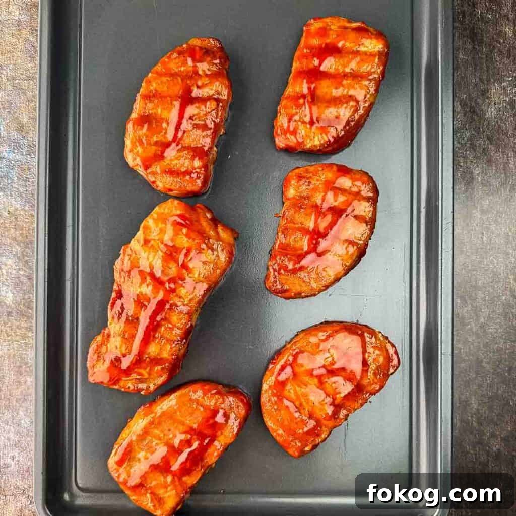 Smoked Thin-Cut Pork Chops on a Traeger Grill 8 Cooked pork chops on a baking sheet, resting for a few minutes before serving.