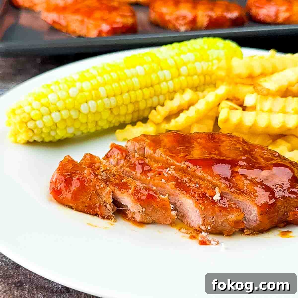 Smoked Thin-Cut Pork Chops on a Traeger Grill 10 A sliced pork chop on a white plate, with glistening sauce and a tender interior.