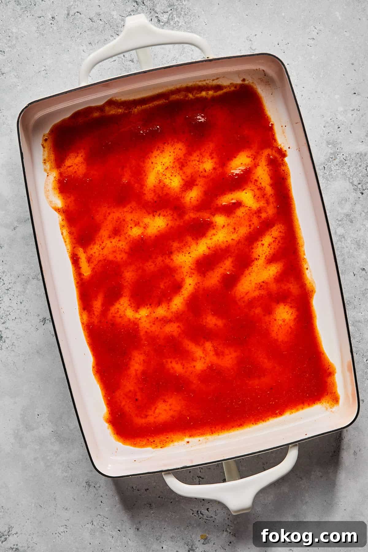 Chicken and Black Bean Enchiladas with Tangy Salsa Verde 5 enchilada sauce at the bottom of a casserole dish