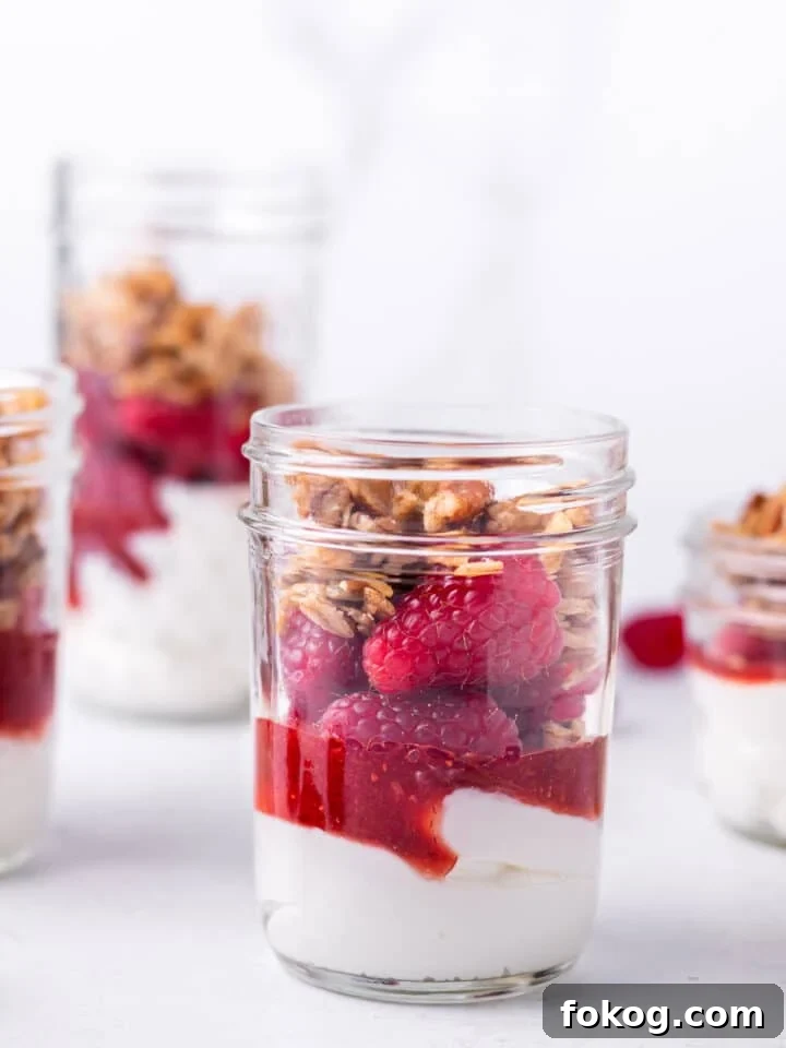 Creamy Raspberry Parfait Recipe with Crunchy Granola 2 small jar with plain Greek yogurt, raspberry jam, fresh raspberries and maple pecan granola