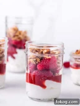 small jar with greek yogurt, raspberry jam, raspberries and homemade granola