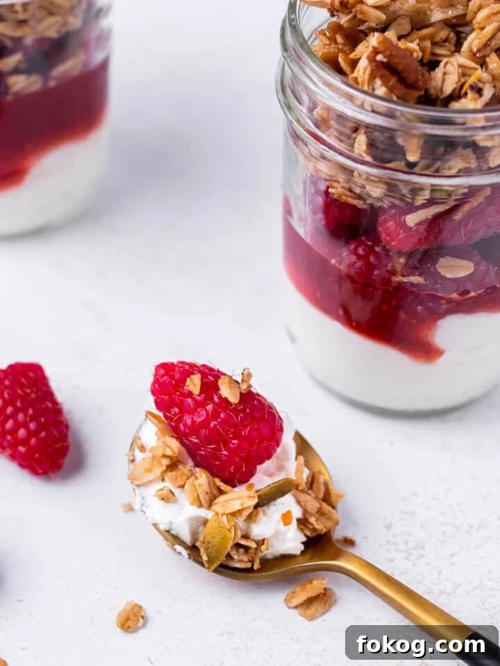 Creamy Raspberry Parfait Recipe with Crunchy Granola 10 bite of yogurt, granola and a fresh raspberry on a spoon