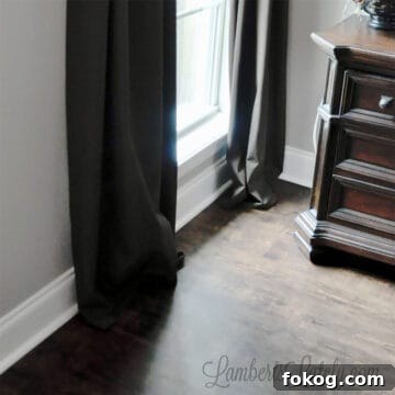 bottom of brown hemmed curtain panels hung on a window next to table.