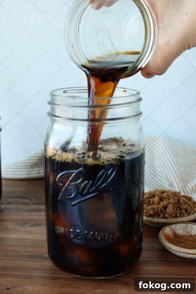 Iced Brown Sugar Latte Recipe — Creamy Cold Coffee Drink 5 Iced coffee being poured into a large mason jar.