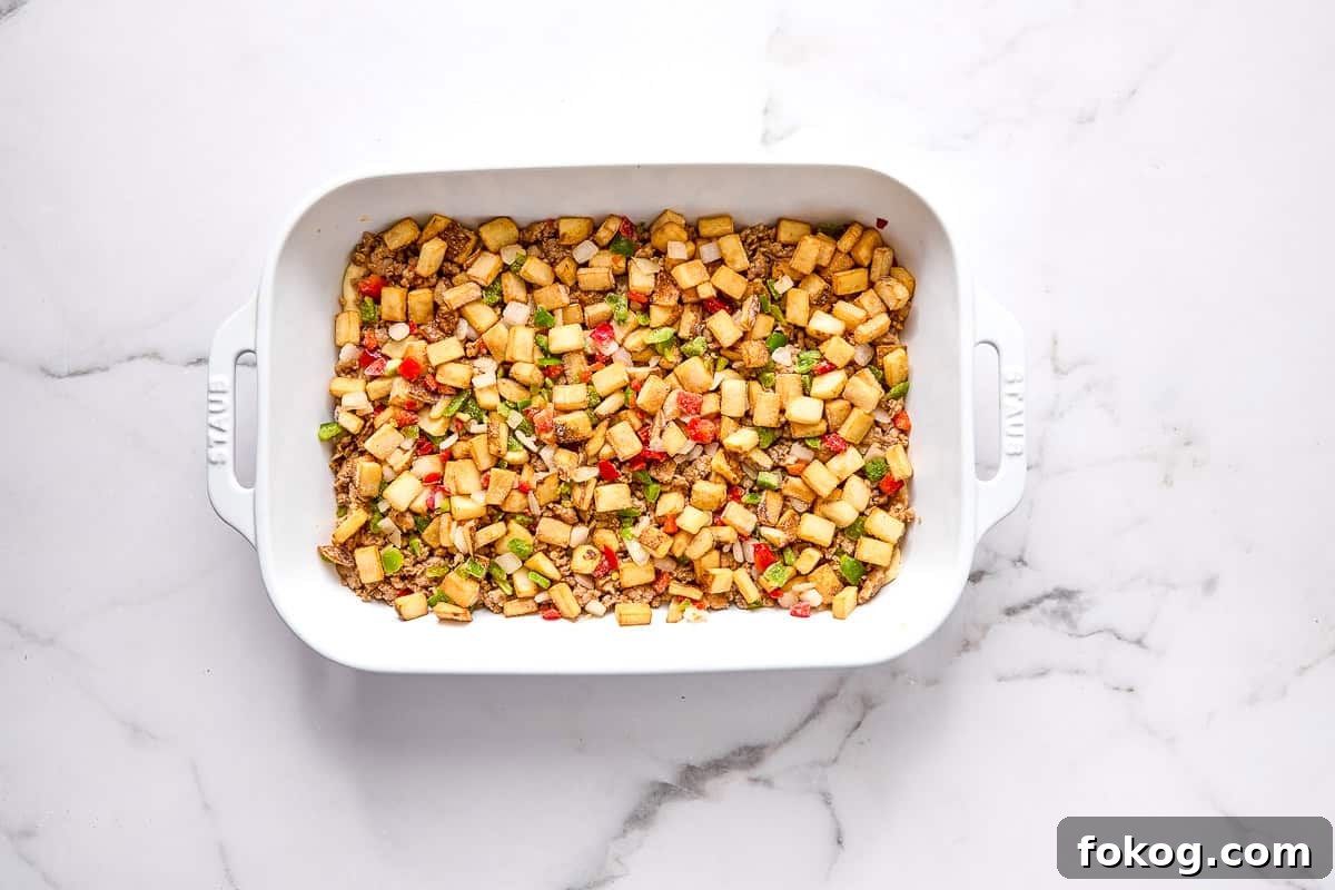 Festive Christmas Breakfast Casserole with Sausage and Cheese 5 Sausage and potatoes in baking dish.