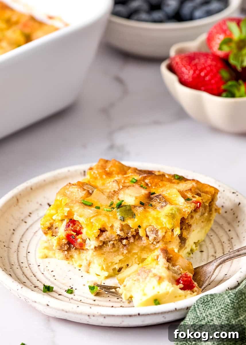 Festive Christmas Breakfast Casserole with Sausage and Cheese 9 Slice of Christmas morning casserole on plate with fork.