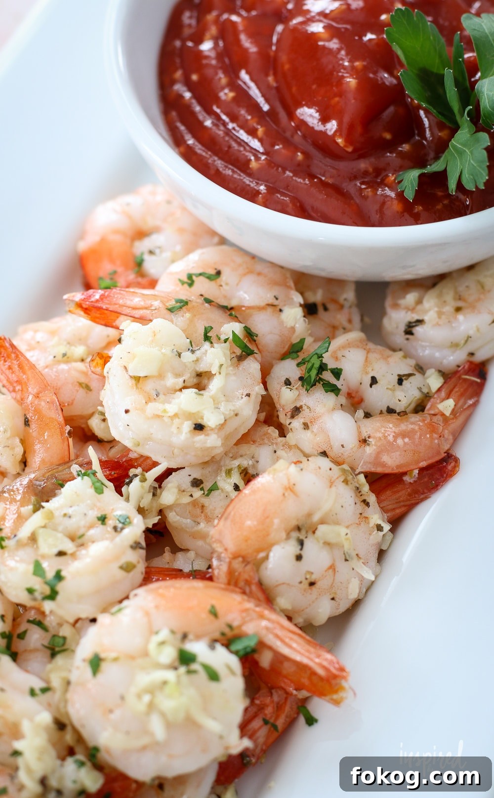 parmesan roasted shrimp on a plate with cocktail sauce in a bowl.