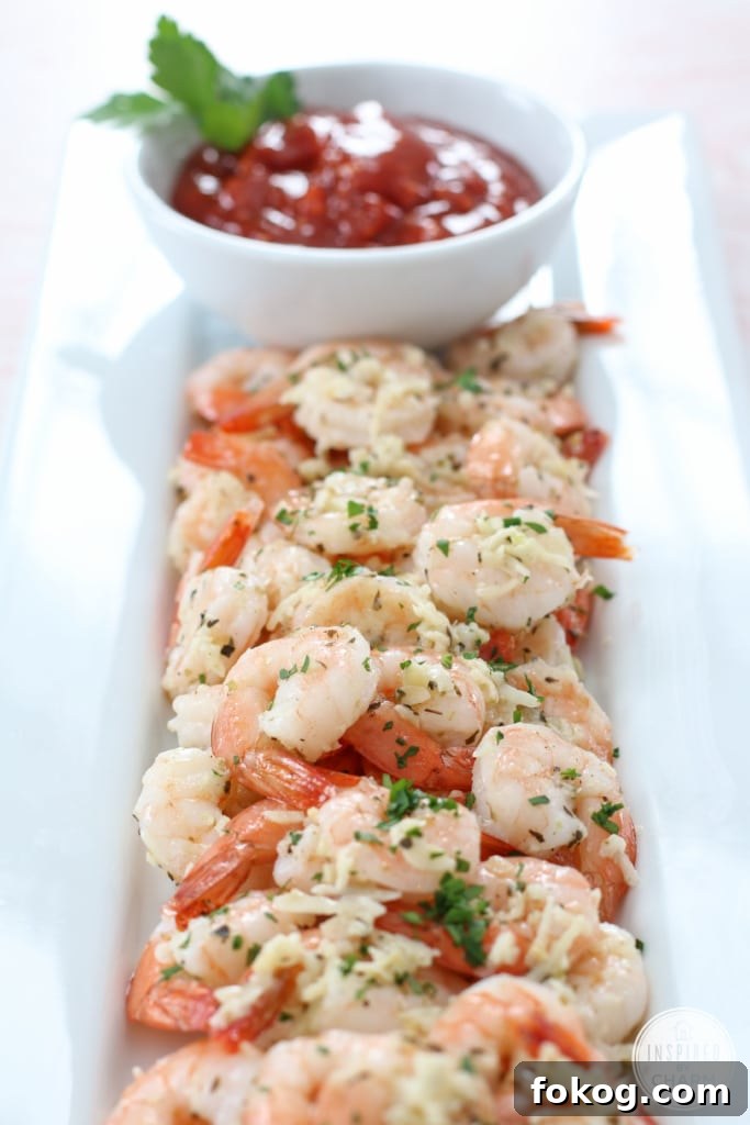 Roasted Parmesan Garlic Shrimp on a platte with a small bowl of cocktail sauce for dipping.