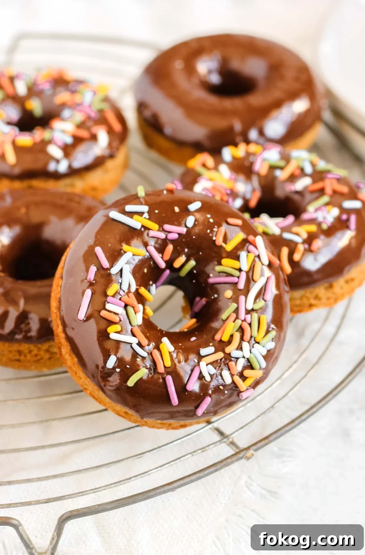 Close up of sprinkled chocolate donut on a cooling rack.