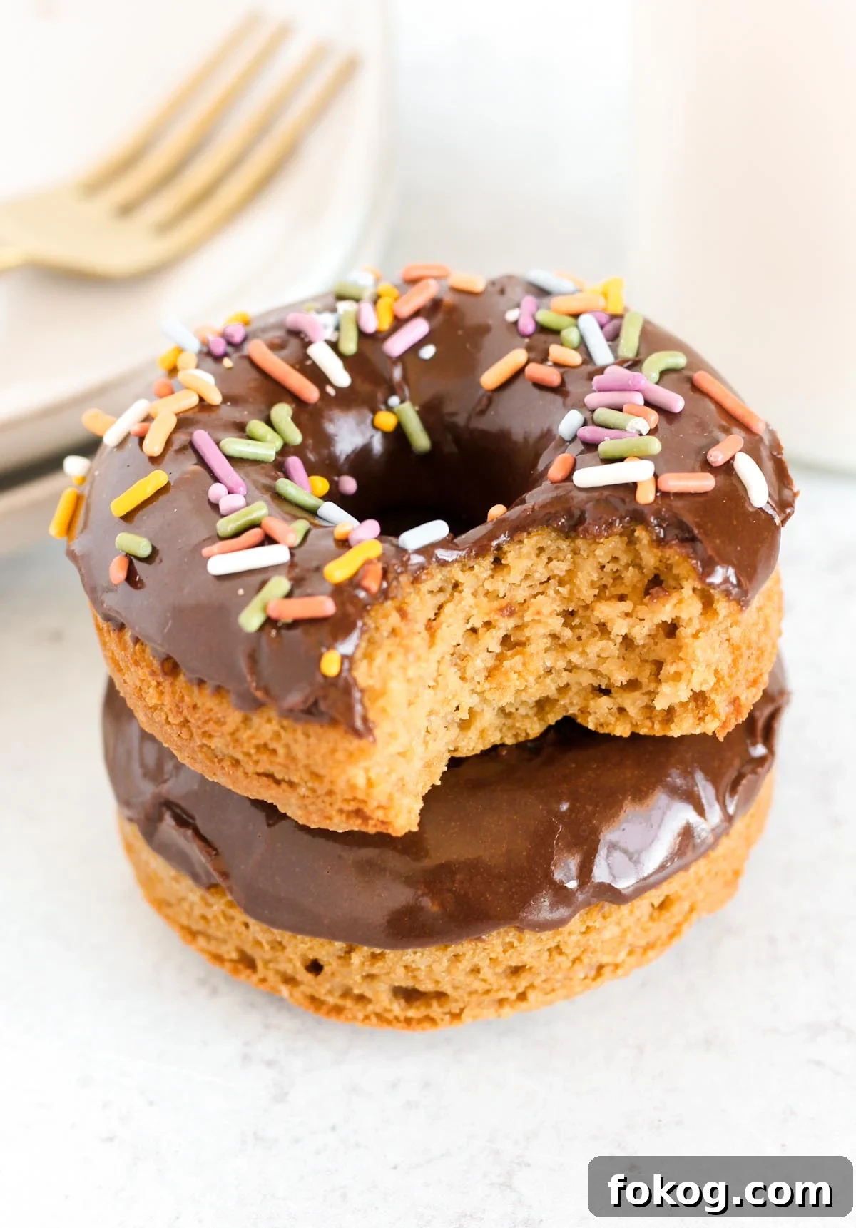 Chocolate covered donut with sprinkles with a bit taken out of it.