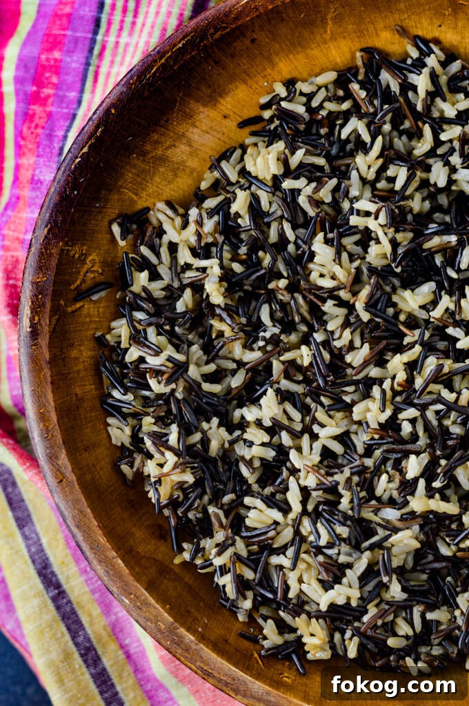 Hearty Chicken and Wild Rice Soup Recipe for Cozy Nights 3 A wooden bowl holds wild and brown rice. A colorful napkin sits next to it.