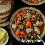Two bowls of wild rice chicken soup loaded with carrots, onions and celery.