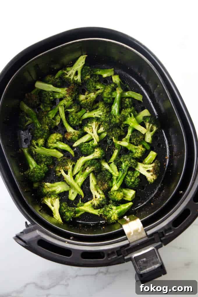 Broccoli in an air fryer basket.
