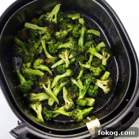 Broccoli in an air fryer basket.