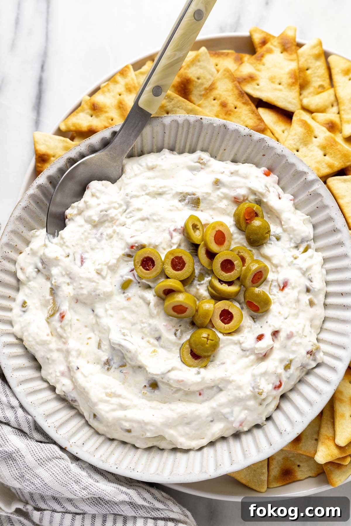 Creamy 10-Minute Olive Dip Recipe for Parties and Snacks 2 Bowl of homemade olive dip on a plate of pita chips.
