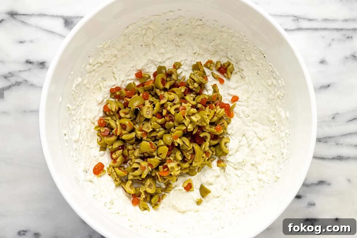 Creamy 10-Minute Olive Dip Recipe for Parties and Snacks 5 Chopped olives added to creamy olive dip.