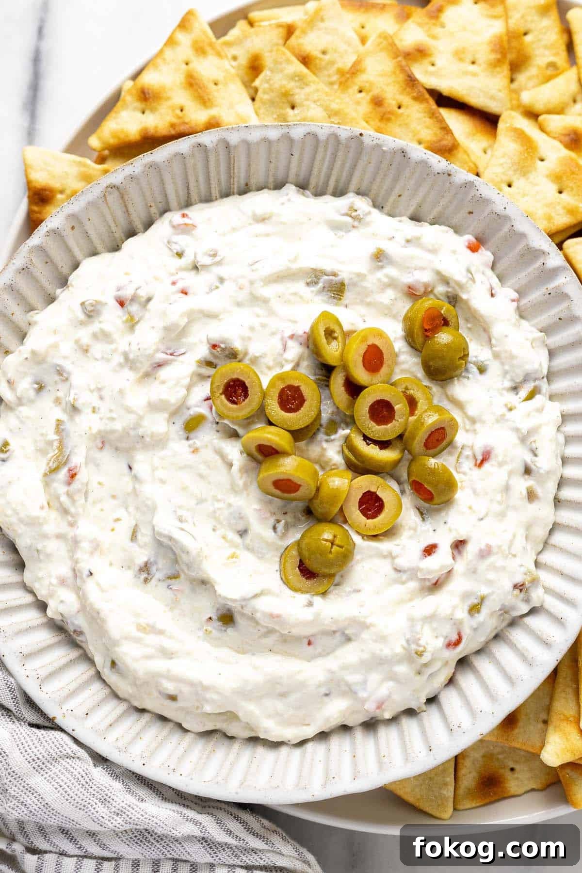 Creamy 10-Minute Olive Dip Recipe for Parties and Snacks 7 Bowl of olive dip on a plate of pita chips.