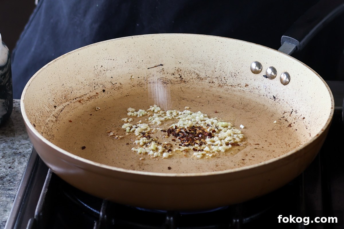 adding garlic and pepper flakes to the pan