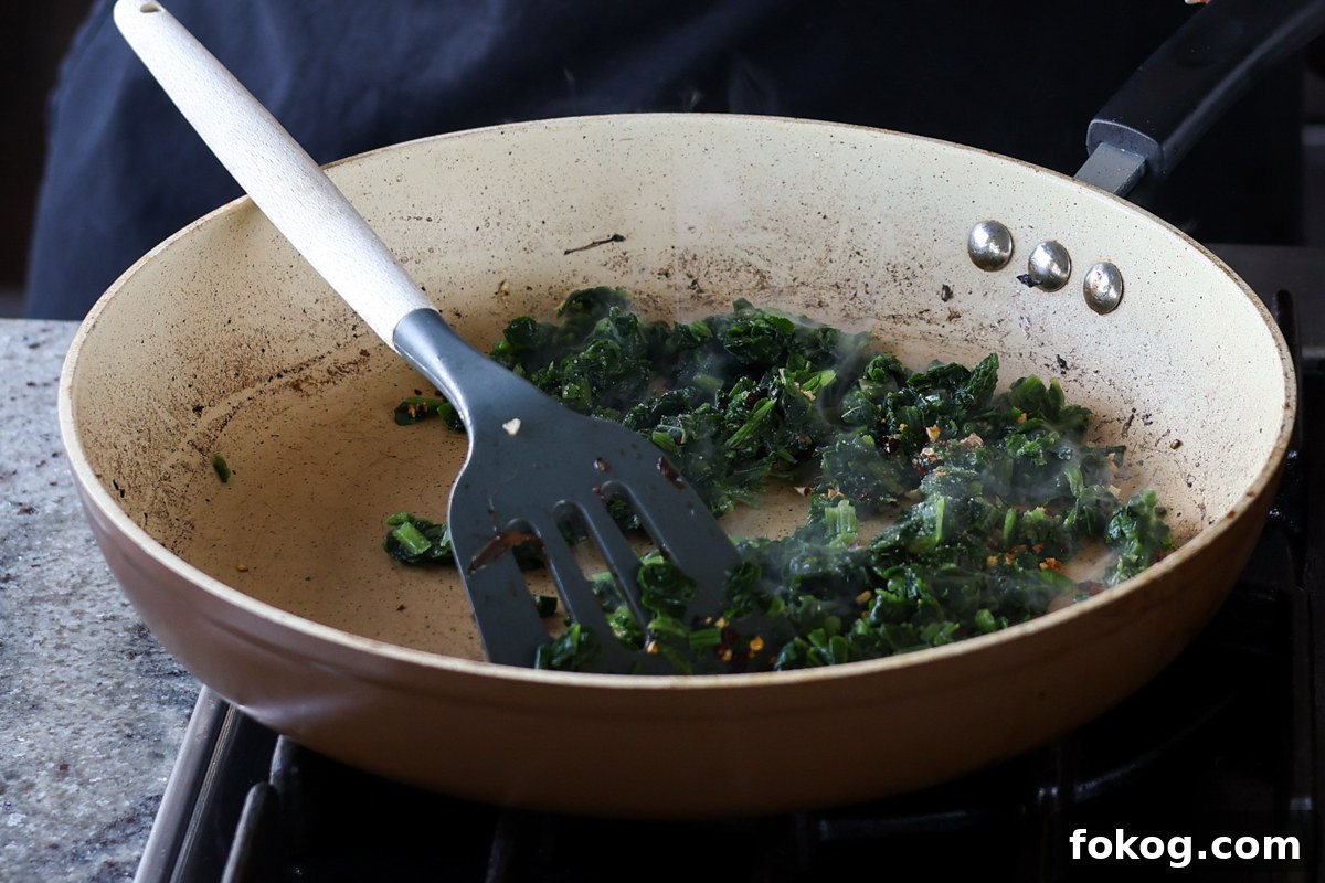 adding spinach to the garlic mixture in the pan
