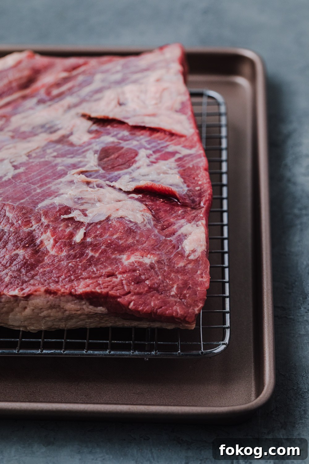 Cranberry-Braised Brisket: A Surprising Holiday Roast Delight 3 Fresh piece of brisket on a wire rack on a baking sheet.