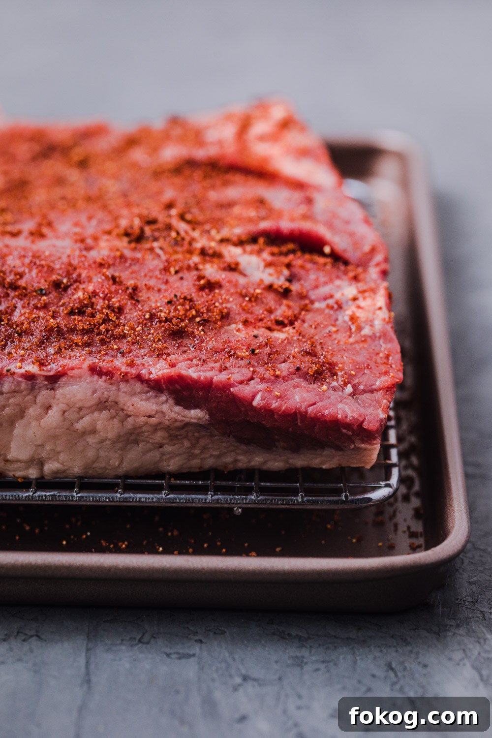 Cranberry-Braised Brisket: A Surprising Holiday Roast Delight 5 Brisket covered in the rub on a wire rack on a baking sheet.