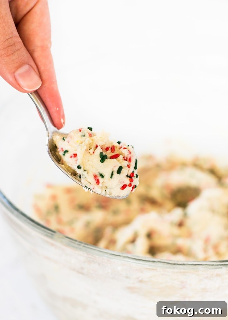 hand holding spoon of edible sugar cookie dough