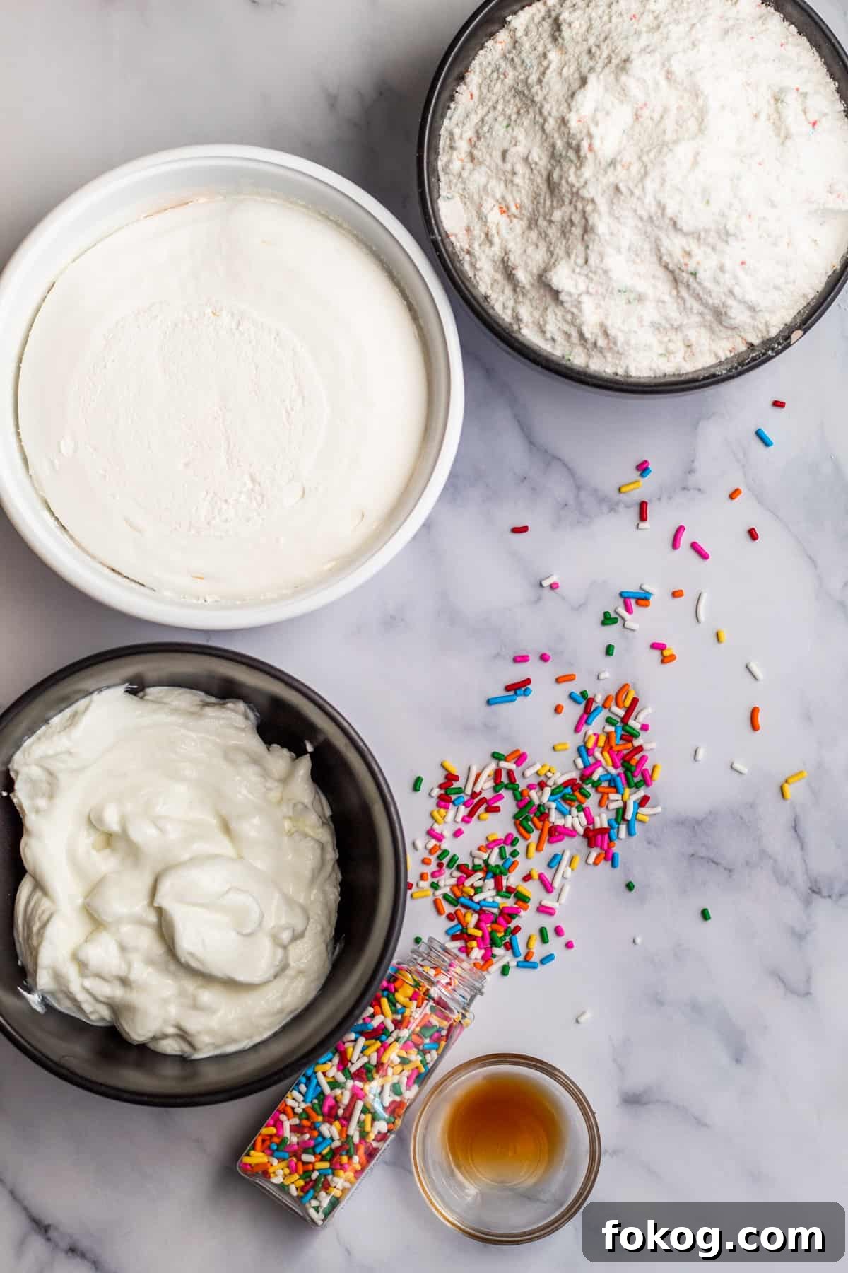 Overhead shot of ingredients laid out on a marble table for funfetti dip.