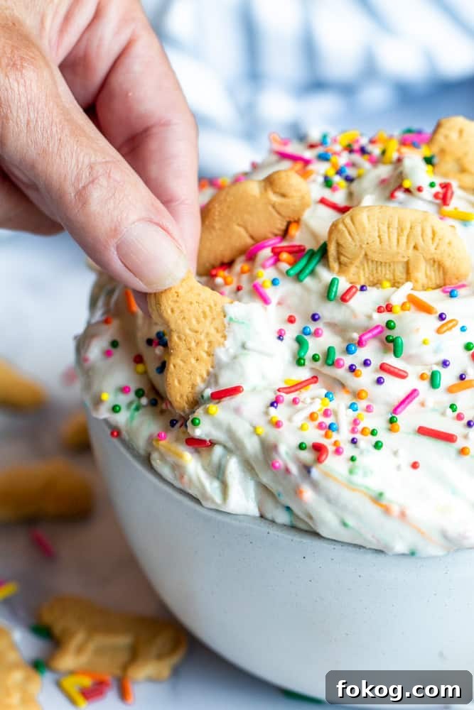 Hand dipping animal cracker in dunkaroo dip.