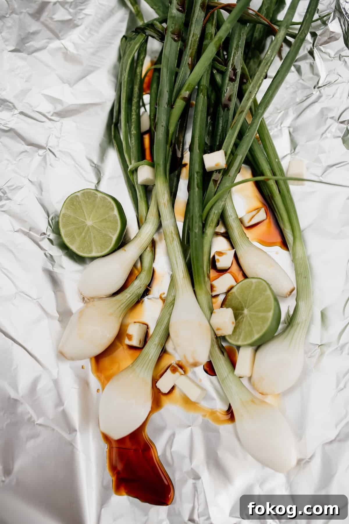 Grilled Spring Onions with Garlic Lime Butter 4 spring onions on a piece of foil with soy sauce and lime for grilling
