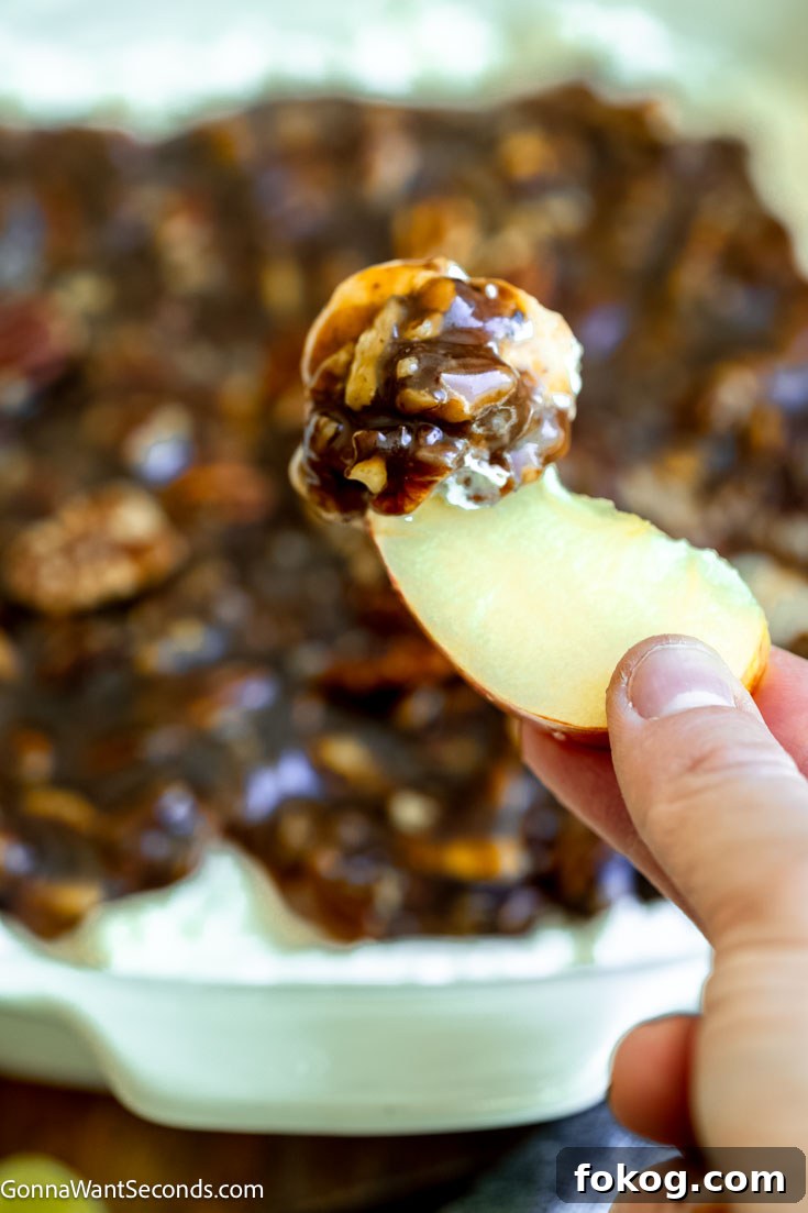 scooping pecan pie dip with cream cheese with an apple slice