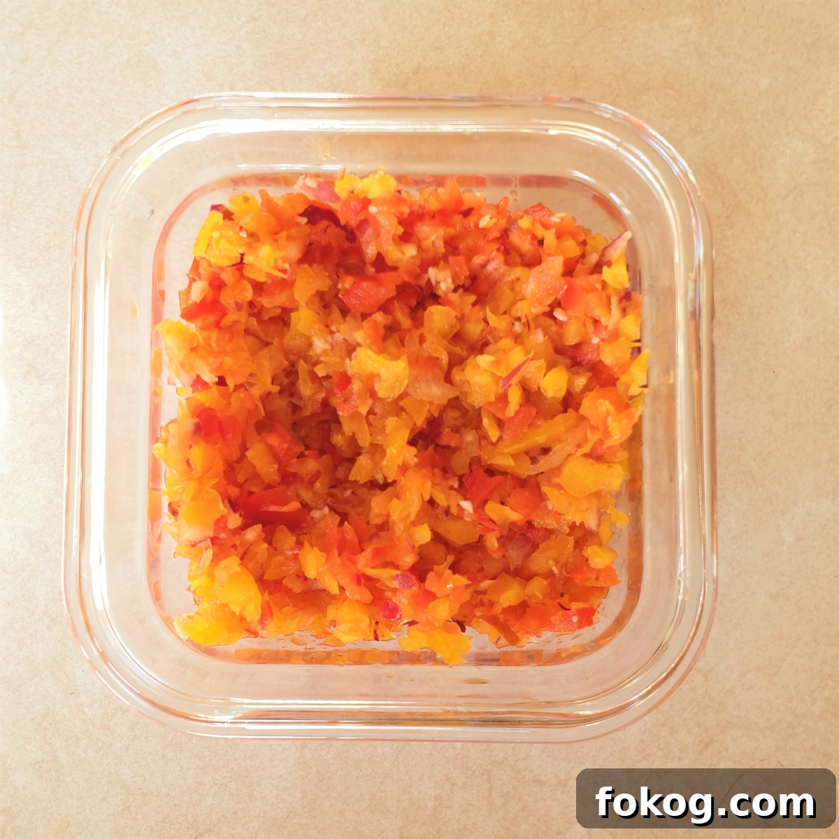 A dish of chopped red and yellow peppers and red onion.
