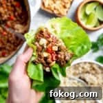 Close-up of a hand holding a healthy Asian beef lettuce wrap.