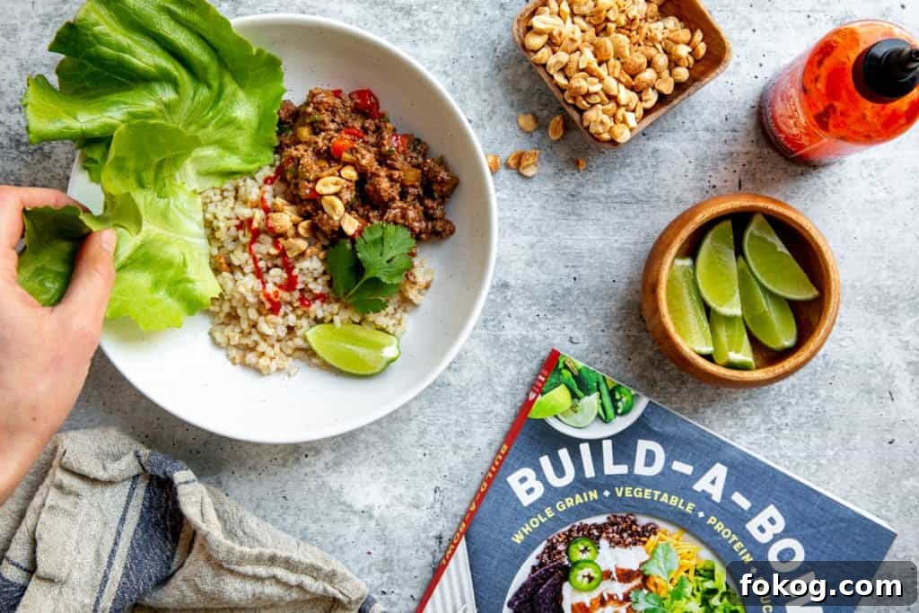 A hand grabbing a lettuce leaf from a bowl to make a beef lettuce wrap.